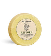 A round, pale yellow bar of soap labeled 'RESTORE' by Bee Vee Clean, photographed on a clean white background.