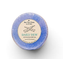 Load image into Gallery viewer, A single round bar of soap wrapped in clear plastic with a cream-colored paper label that reads 'Bee Vee Clean by BVTalks, Daily Dew'. The soap itself has a mottled blue and purple coloration, photographed on a clean white background.

